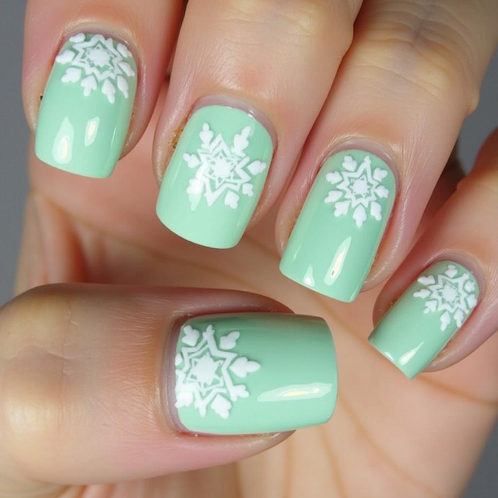 Mint green nails with white snowflake nail art