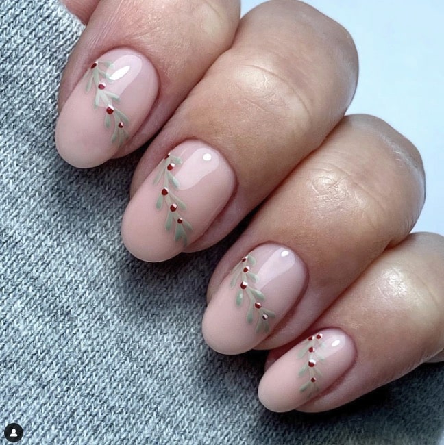 Sheer nude nails with tiny painted mistletoe sprigs of green leaves and red berries.