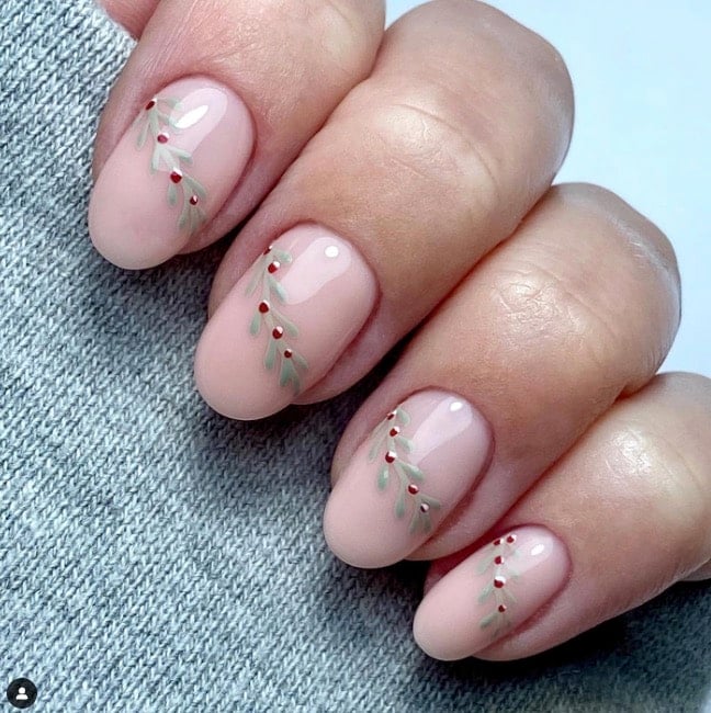 Sheer nude nails with delicate green mistletoe sprigs and tiny red berries