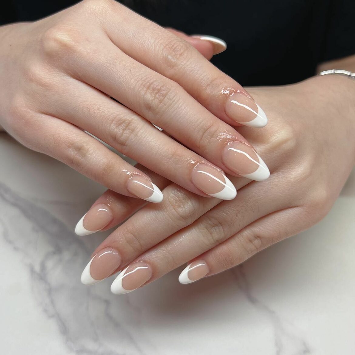 Almond-shaped nails with a classic white French tip manicure