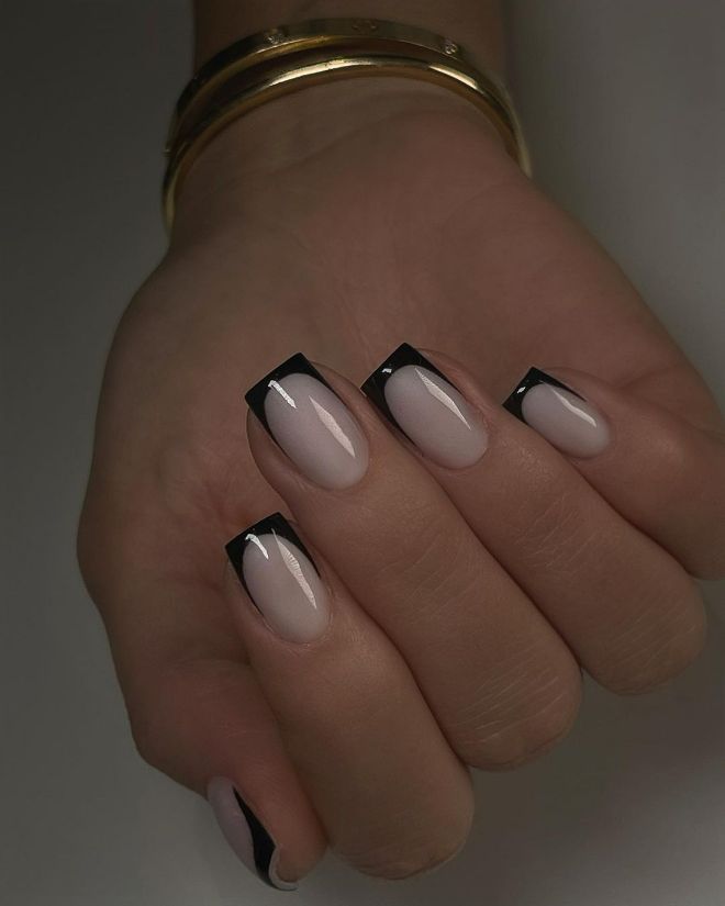 Square nails with a milky nude base and glossy black French tips