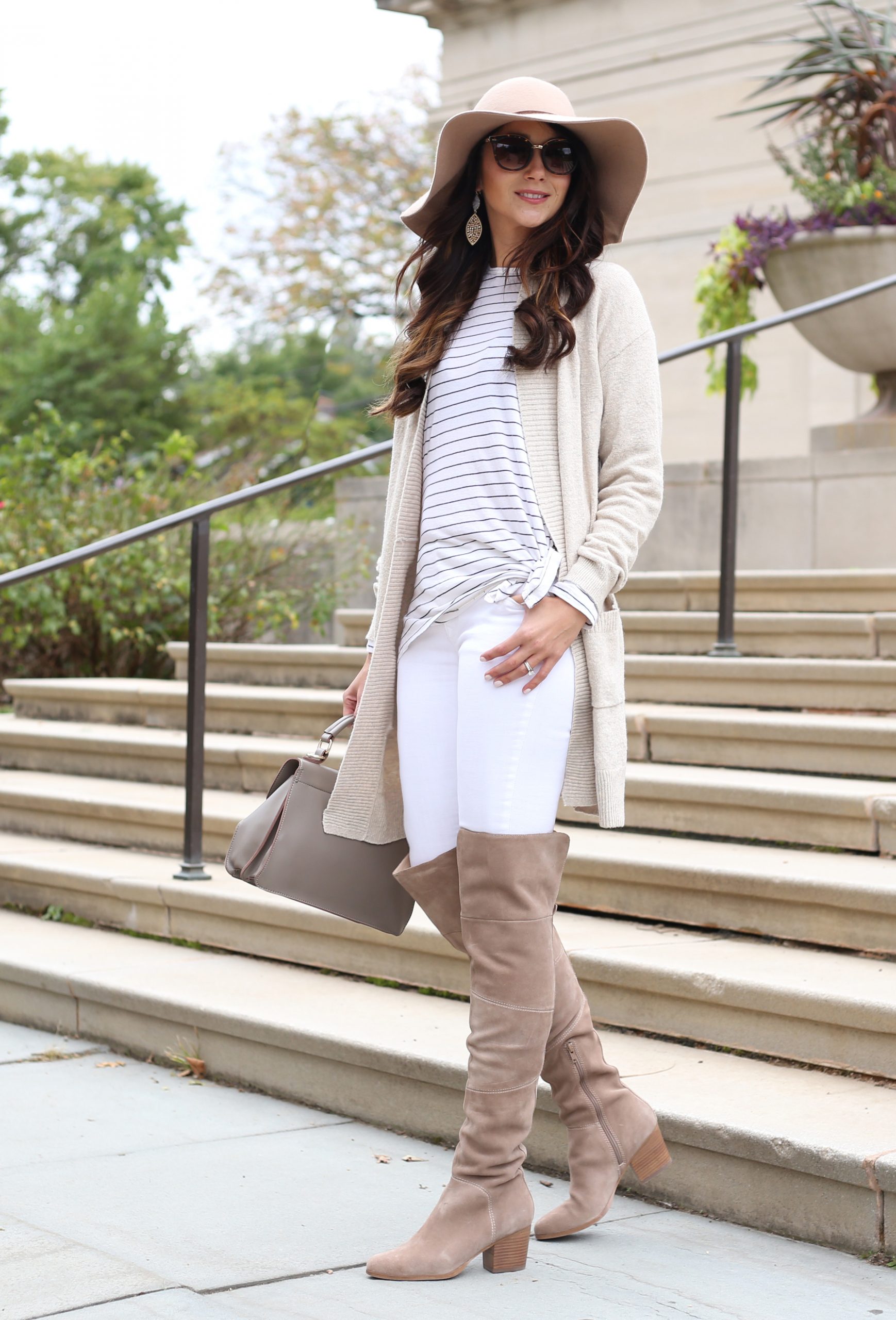 Taupe suede over-the-knee boots with white skinny jeans and a long beige cardigan