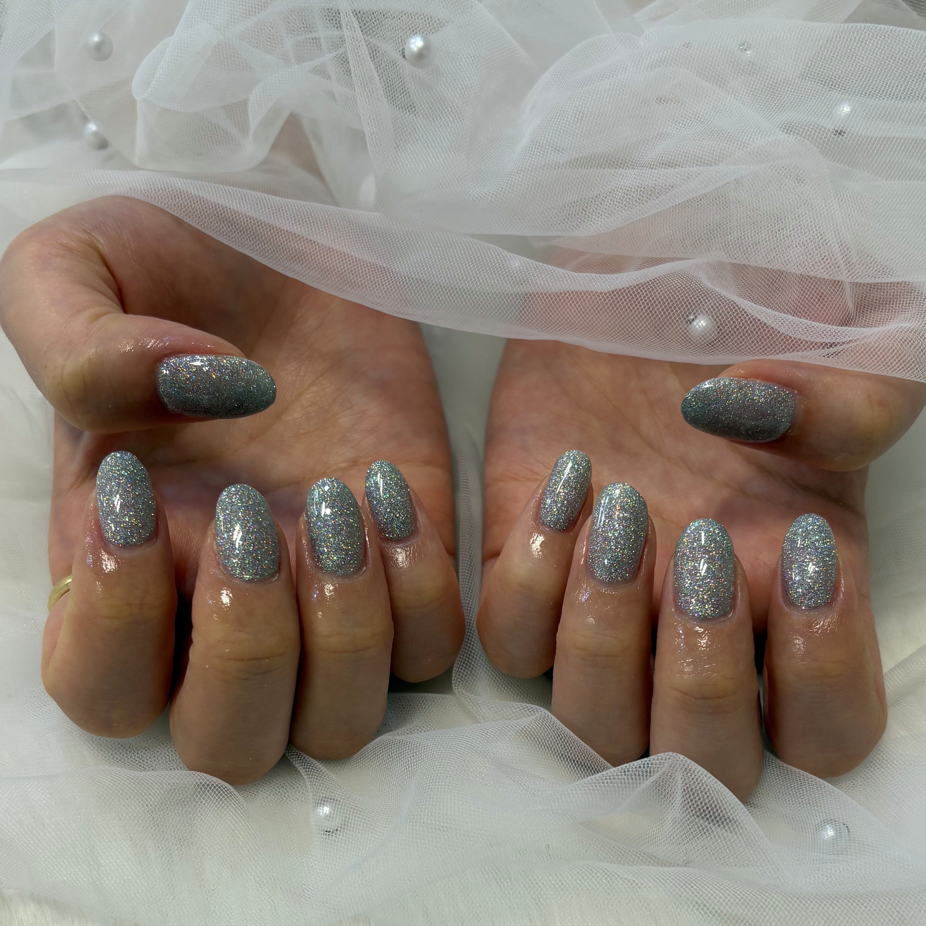 Short oval nails in silver gray holographic glitter polish