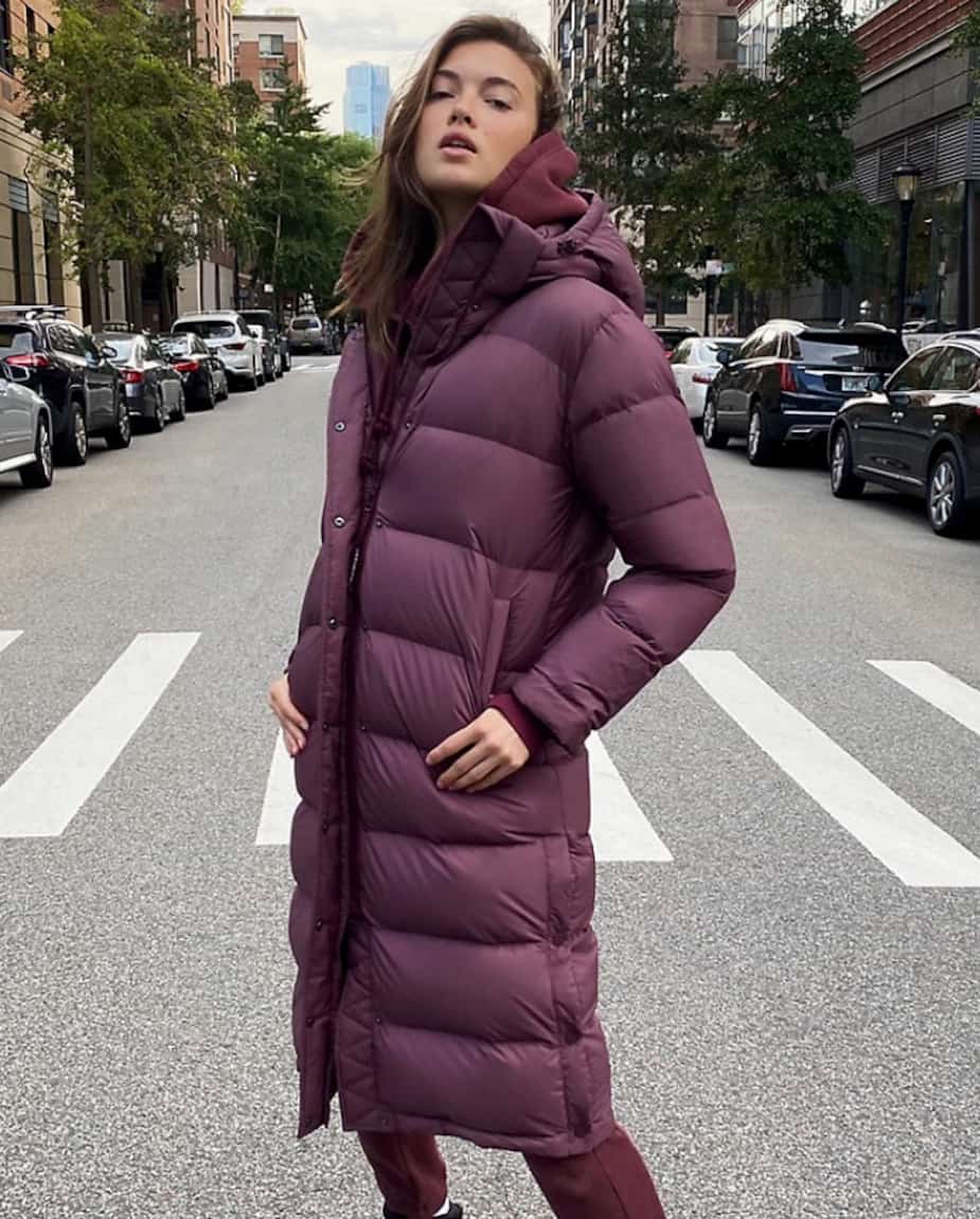 Woman in a long plum puffer coat with matching plum hoodie and trousers