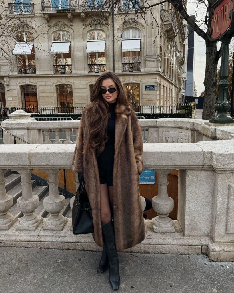 Woman in a long brown faux fur coat and black knee-high boots in Paris