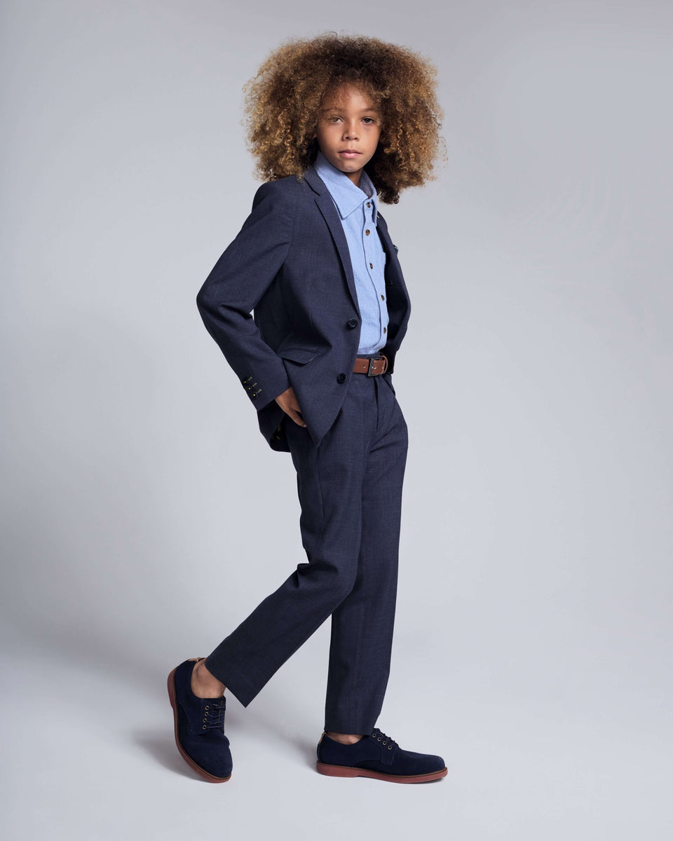 A boy wearing a navy peacoat with a sweater and corduroy pants