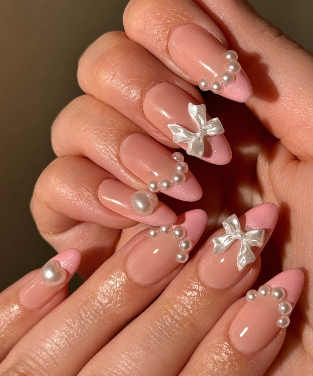 Pink nude almond nails with pearl accents and 3D bows