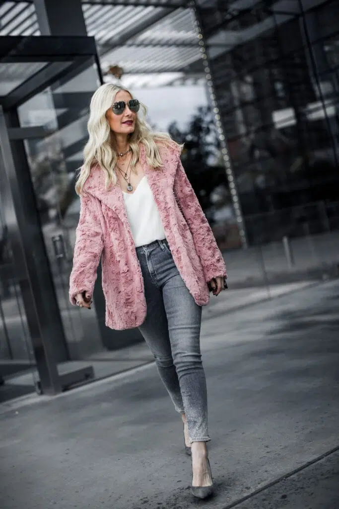 Woman in a blush-pink teddy coat with grey skinny jeans and grey heels