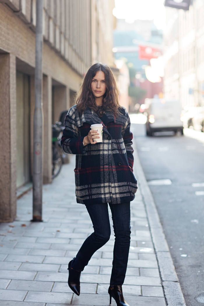 Woman wearing a navy and red plaid wool shacket with dark skinny jeans and black pointed ankle boots