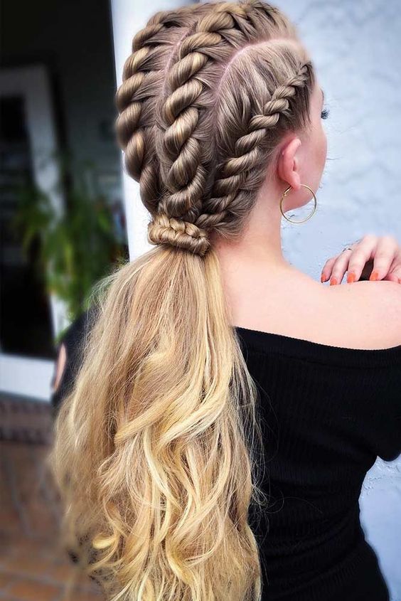 Long blonde hair with rope braids along the scalp gathered into a low wavy ponytail