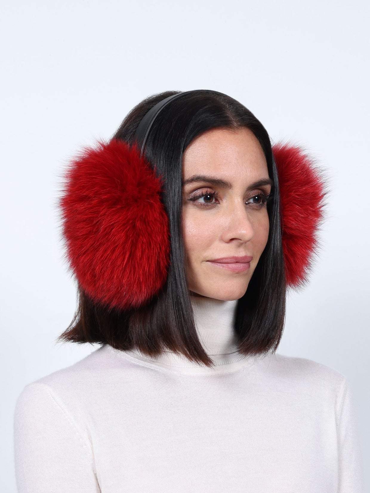 Woman wearing red fur earmuffs and a white turtleneck in a studio portrait
