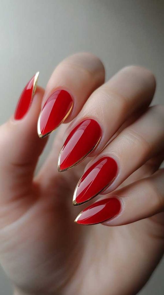 Almond red nails with thin gold chrome outlines along the free edge