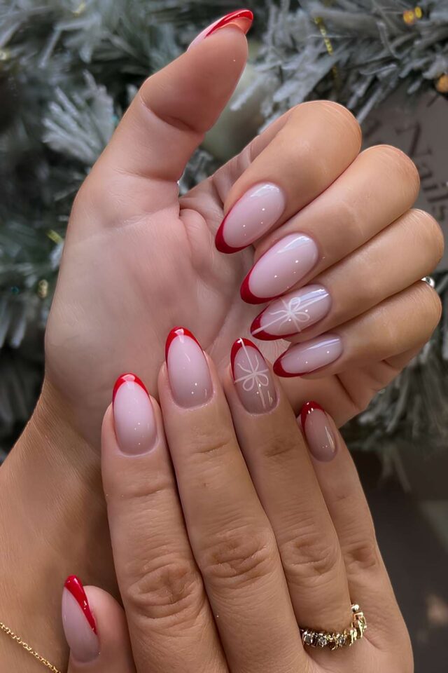 White French tip almond nails with a red bow accent