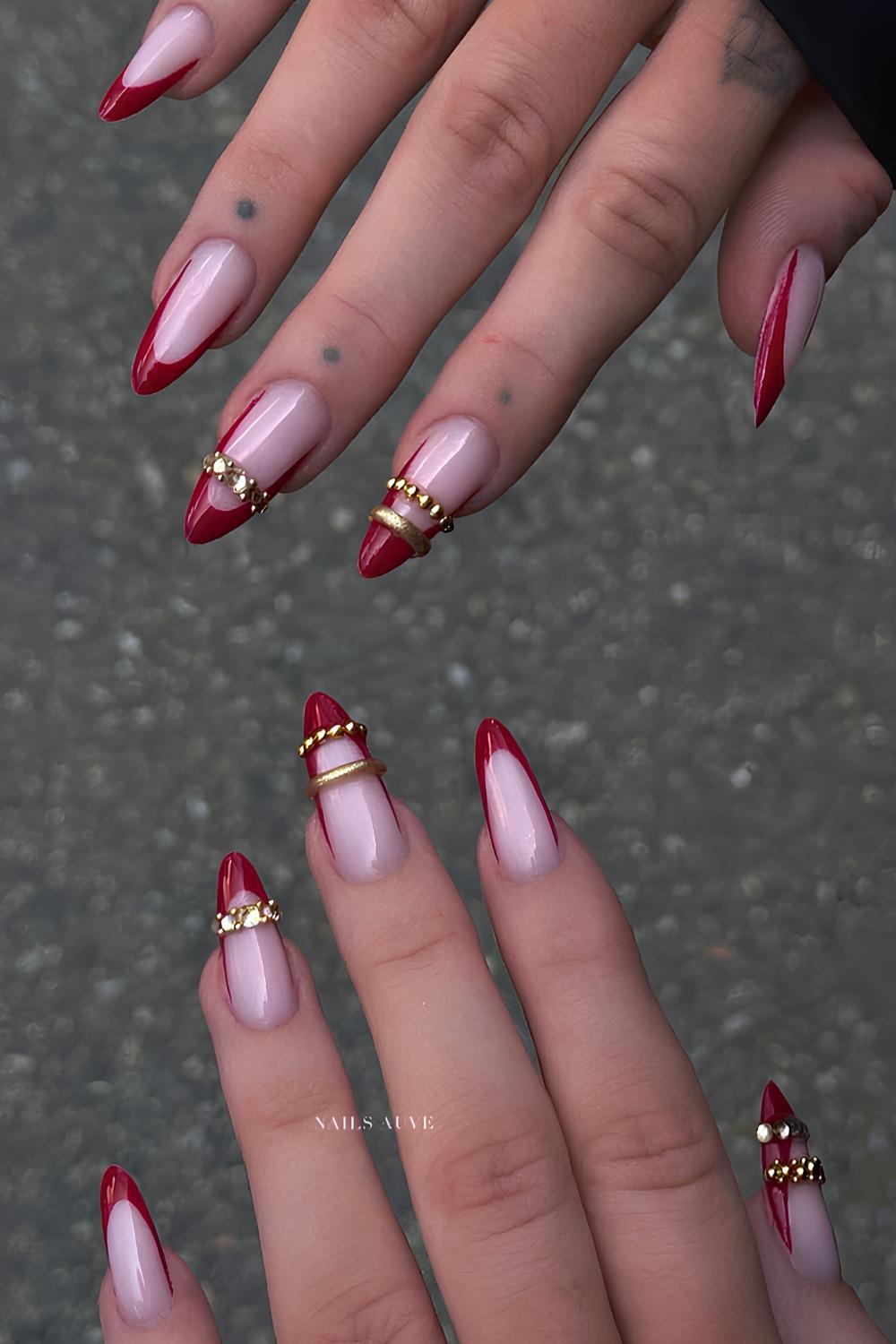 Long stiletto nails with nude bases, red French tips, and 3D gold beaded bangle rings around accent nails