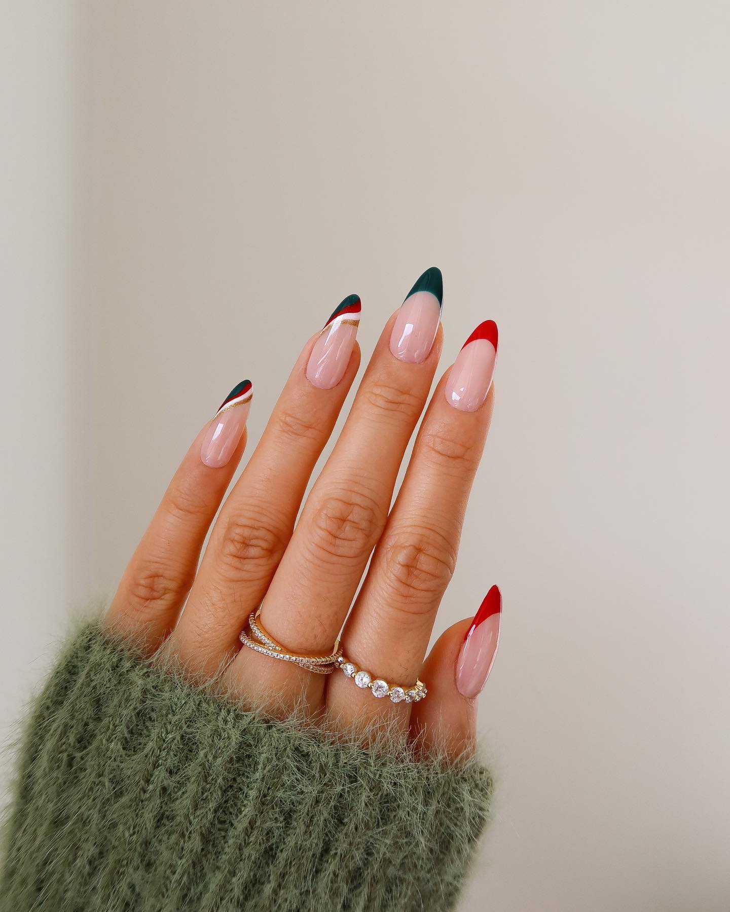 Red and green French tip nails with wavy striped accent nails on a sheer nude base