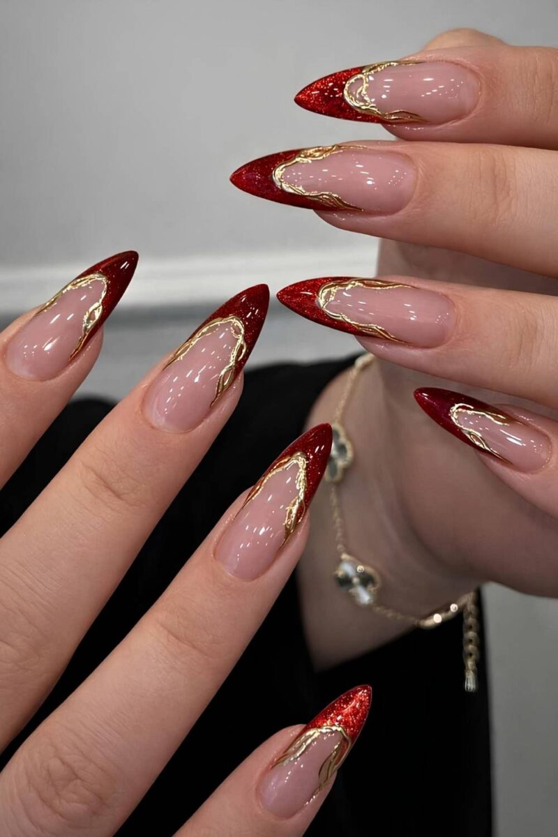 Long stiletto nails with nude base, red glitter cat-eye French tips and gold chrome outlines