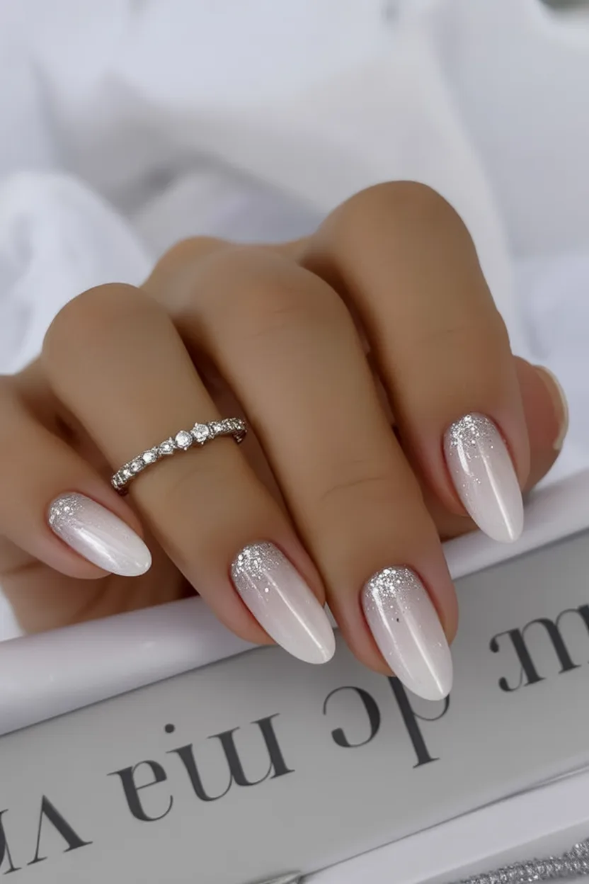 Oval nails with dense silver glitter fading from the cuticle into a sheer nude base