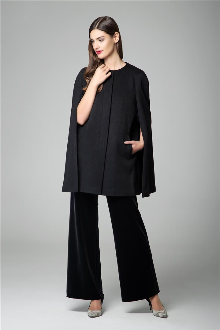 Model wearing a black wool and cashmere cape with tailored wide-leg trousers