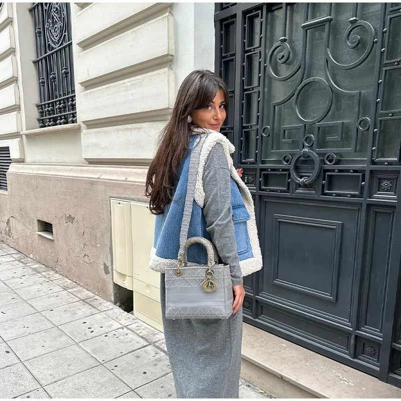 Denim vest with cream shearling trim worn over a grey knit midi dress on a Paris street