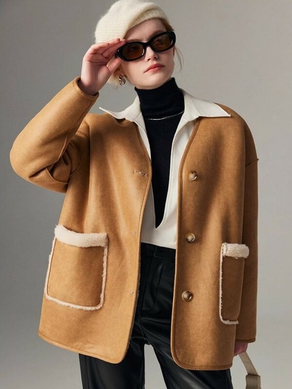 Woman in a tan jacket with shearling pockets and collar, black turtleneck, black leather pants and a cream beanie