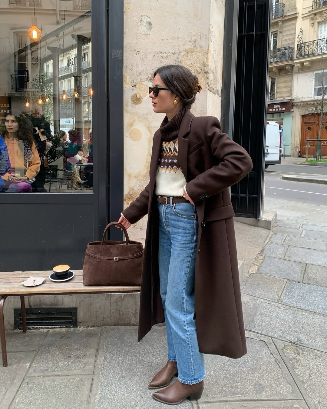 Woman wearing a chocolate brown wool coat with a fair-isle turtleneck sweater, jeans and brown ankle boots