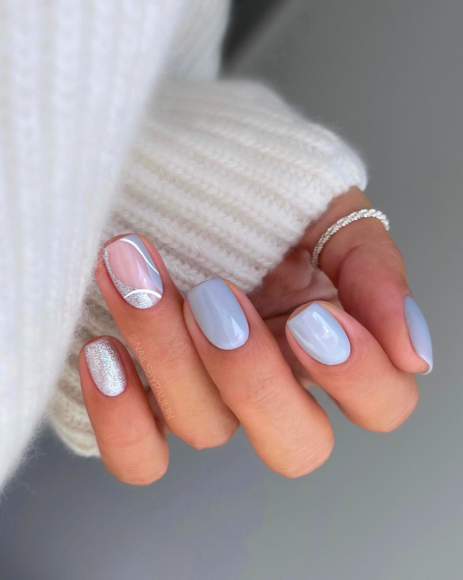 Icy blue nails with silver glitter accents and white swirl line art