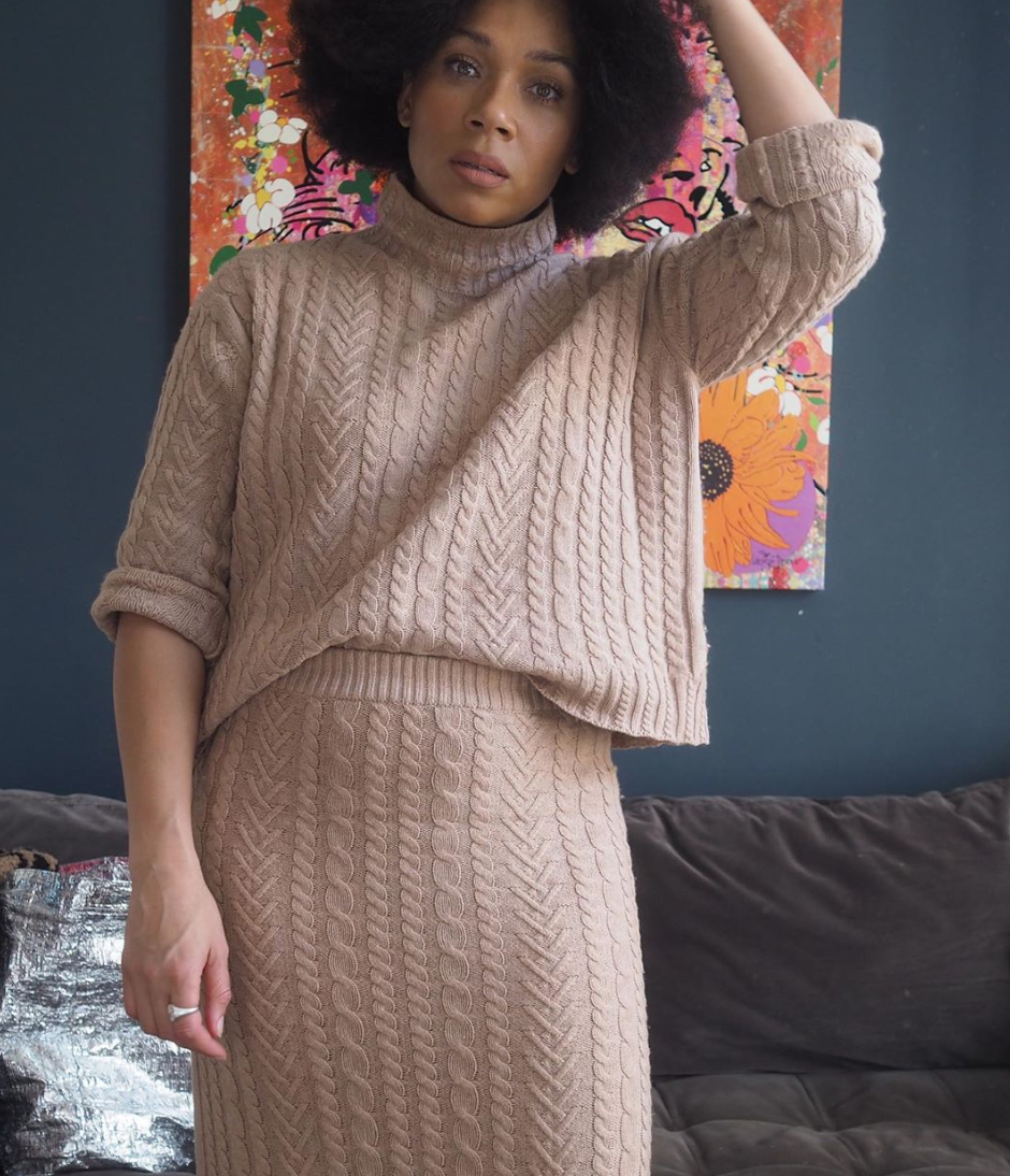 Woman wearing a beige cable-knit turtleneck sweater and matching beige cable-knit midi skirt