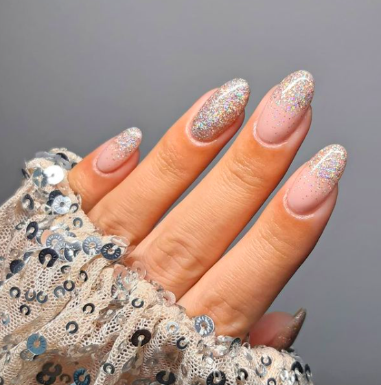 Almond nude nails with holographic silver glitter concentrated at the tips