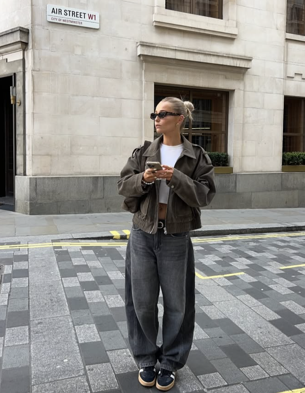 Olive cropped bomber jacket over white baby tee with washed-black barrel-leg jeans and sneakers
