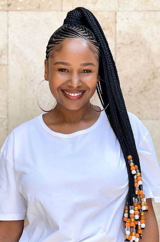 High braided ponytail decorated with orange and white beads