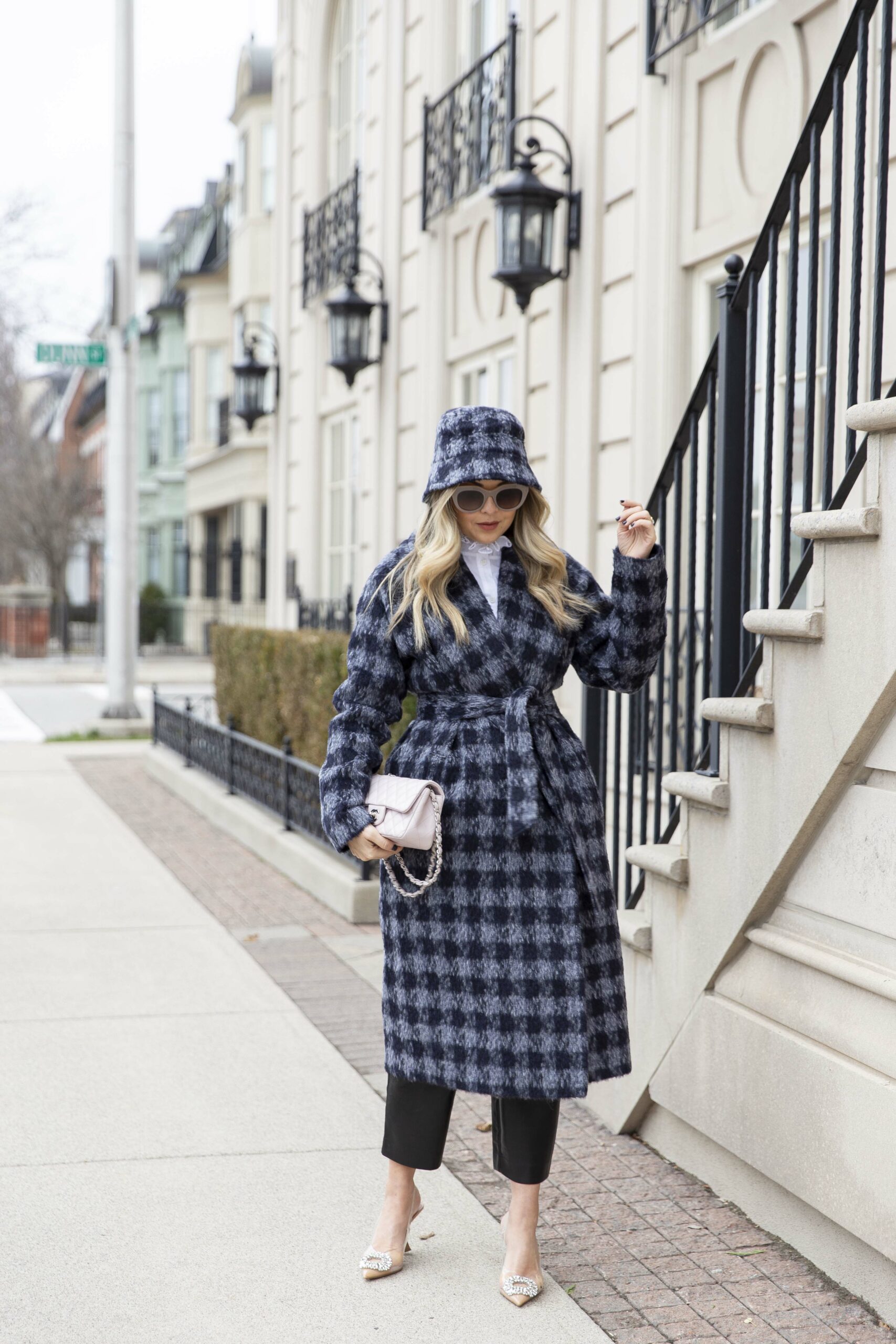 Woman wearing a houndstooth coat over a sleek dark outfit