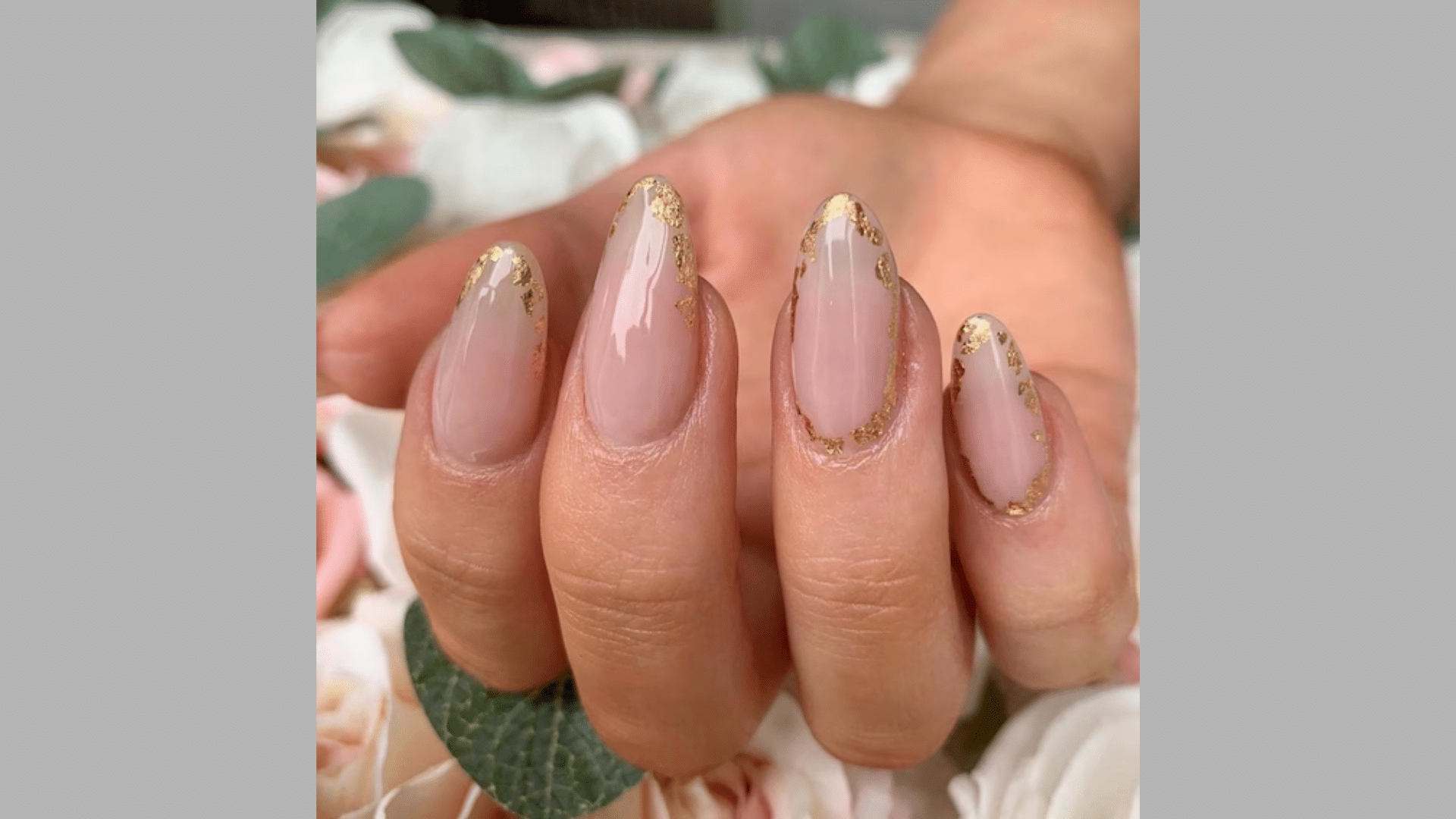 Sheer pink almond nails with gold foil along the tips