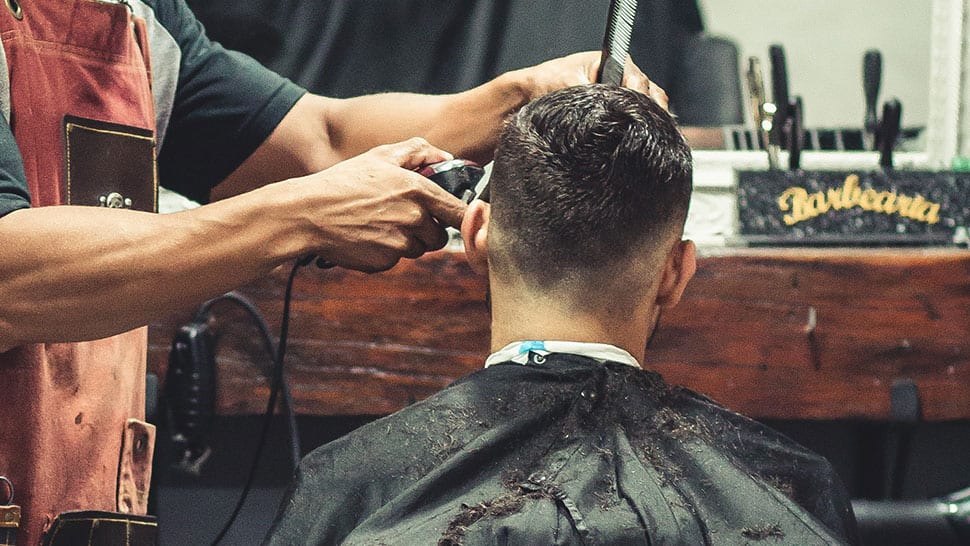 Barber finishing a short faded buzz haircut on a client