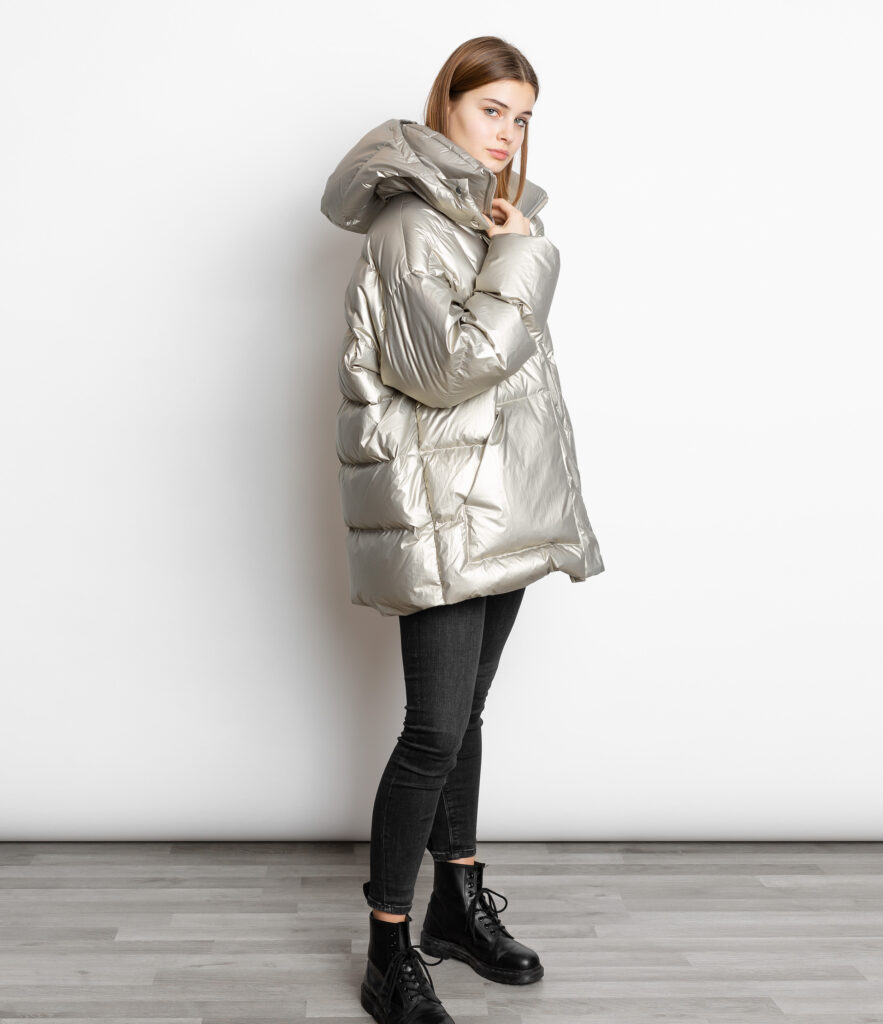 A woman wearing a silver metallic long puffer coat with dark jeans