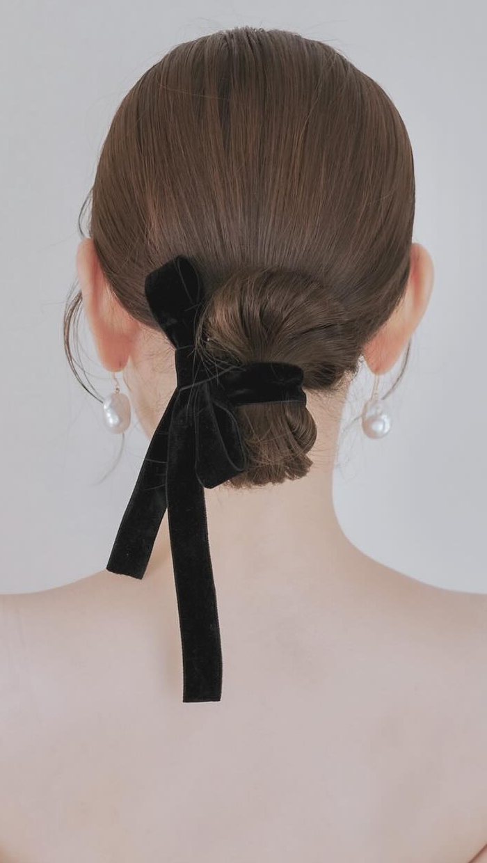 Woman with a simple low bun tied with a black velvet ribbon bow