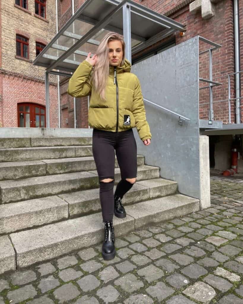Woman styling a puffer jacket with an oversized scarf, structured bag and slim boots