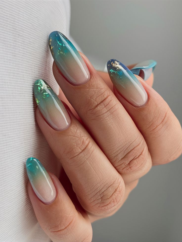 Almond nails with teal-to-turquoise ombre tips fading into sheer nude, with subtle gold foil accents