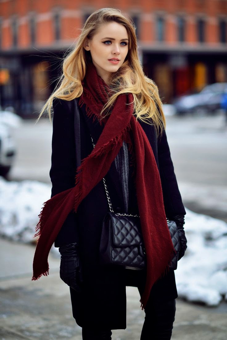 Woman in an all-black winter outfit with a long burgundy scarf as a pop of color