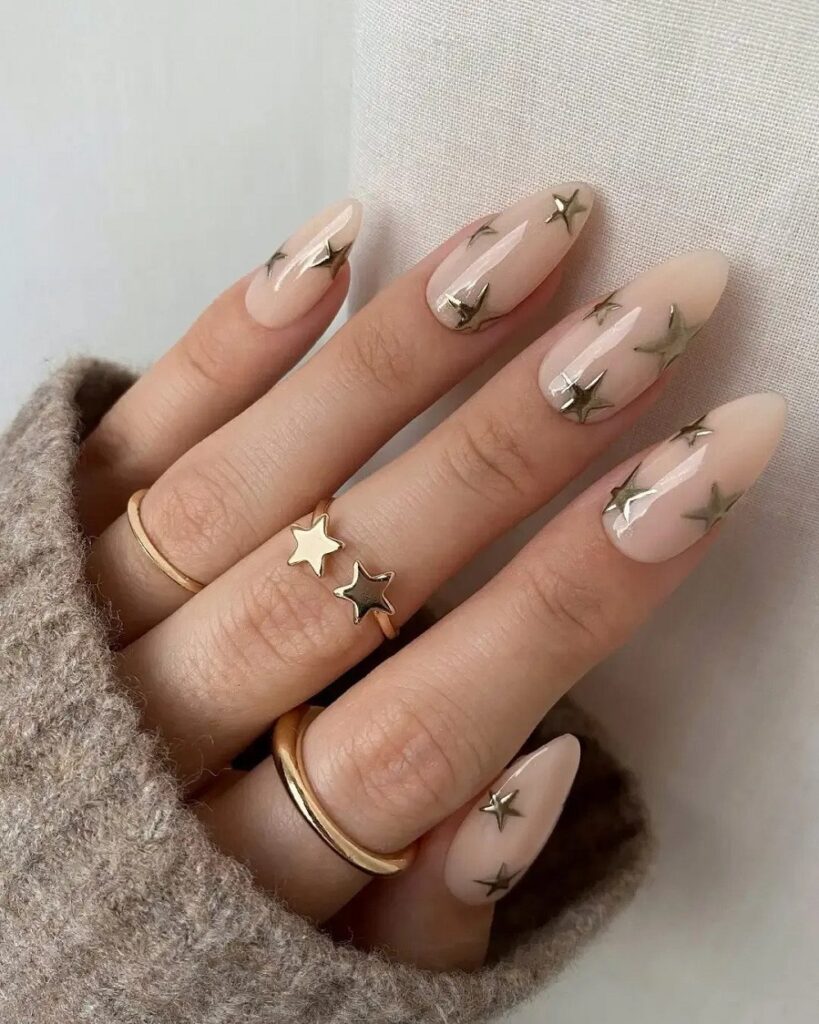 Milky nude almond nails scattered with small gold 3D star studs