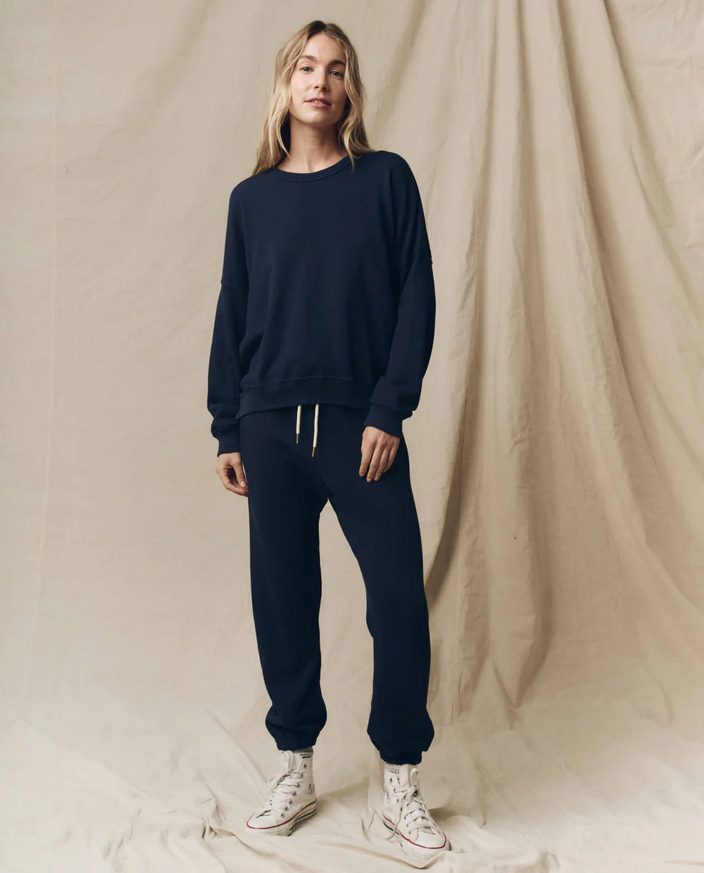 Woman in a navy sweatshirt and matching navy joggers with white sneakers
