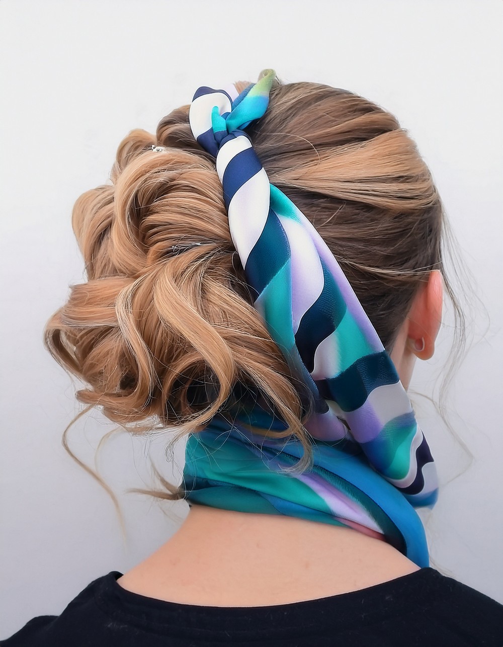 Curly blonde updo wrapped with a teal, blue and white striped silk scarf