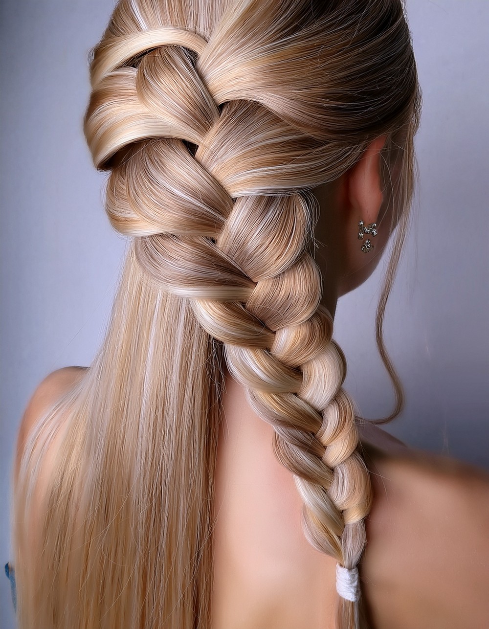 Waterfall braid cascading through long blonde hair left loose below