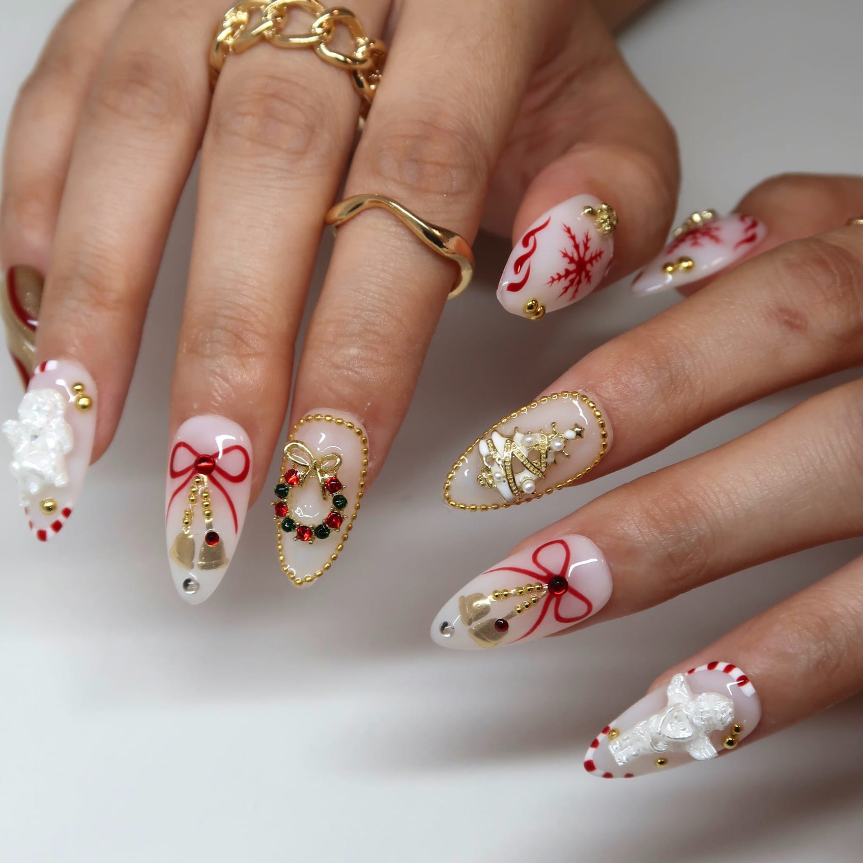 Long white and red Christmas stiletto nails with 3D charms, bows, snowflakes and gold beading