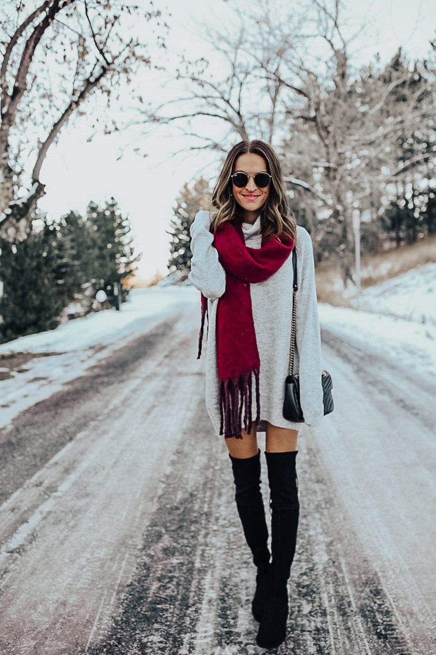 Grey sweater dress with a burgundy scarf and black over-the-knee boots