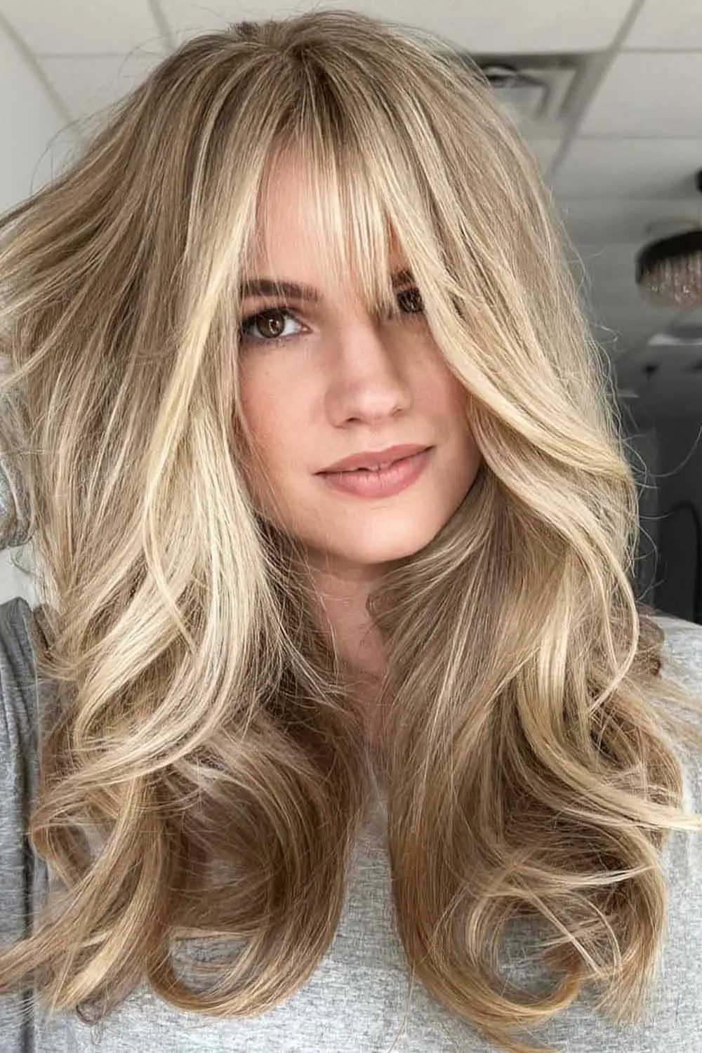 Long blonde hair with curtain bangs and amber lowlights