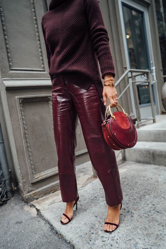 Woman in burgundy vinyl leather pants with a matching burgundy ribbed turtleneck and burgundy heels