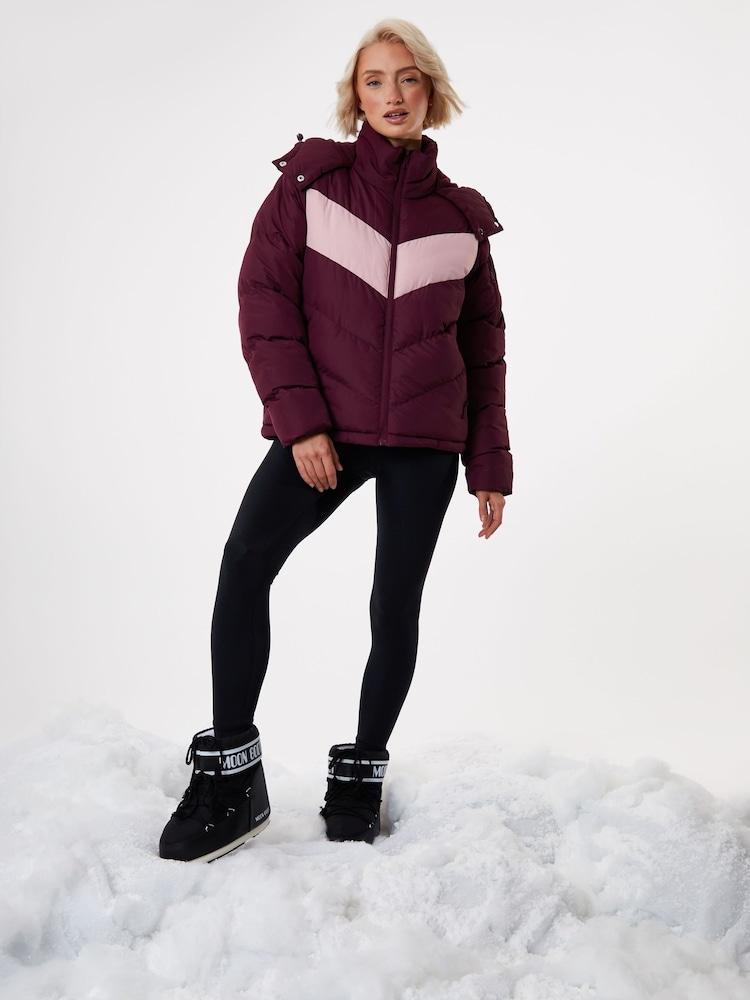 Burgundy puffer jacket with pink chevron, black leggings and black moon boots in snow