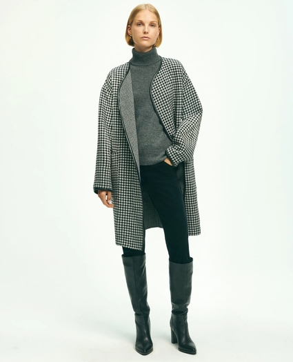 Model wearing a houndstooth check wool coat with a grey turtleneck, black leggings and knee-high boots