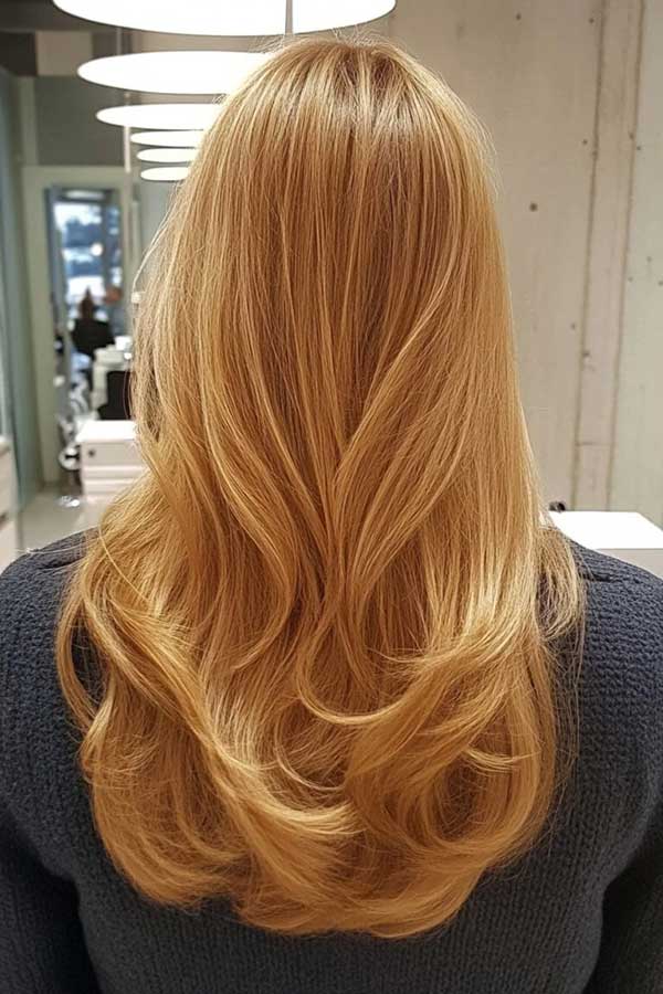 Long golden honey blonde hair with soft loose waves, back view