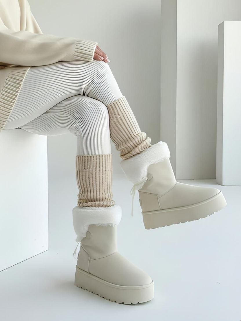 Beige ribbed leg warmers over white pinstripe leggings with a cream sweater and cream platform boots in a studio